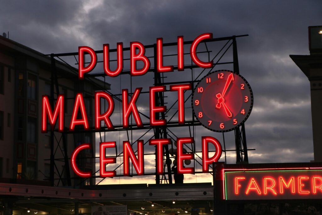 Neon sign of Pike Place Market in Seattle at sunset, highlighting the famous landmark.
